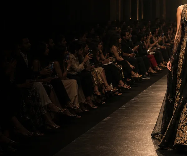Audience members watching a black-and-gold runway show.