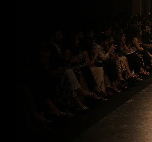 Audience members watching from beside a dimly lit runway.